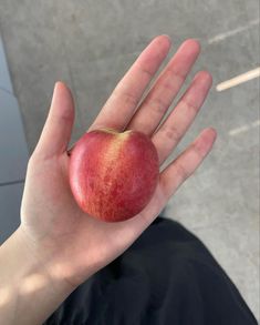 a person holding an apple in their hand on the ground with no one around them