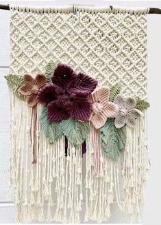 a close up of a wall hanging with flowers and fringes on it's side