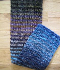 two knitted scarves sitting on top of a wooden floor