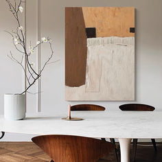 a white table with two chairs and a painting on the wall