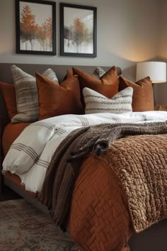 a bed with two pictures above it and pillows on the headboard, in a bedroom