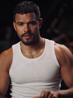 a man in white tank top standing with his hands on his hips and looking at the camera