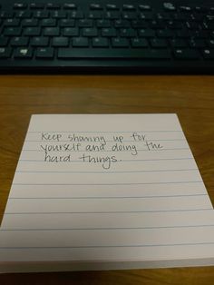 a piece of paper sitting on top of a wooden desk next to a computer keyboard