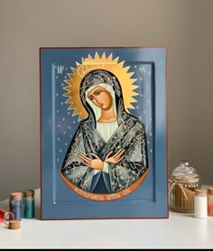 an icon of the virgin mary is displayed in front of some candles and other items