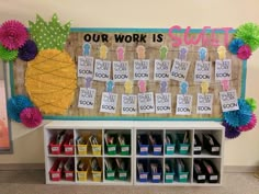 a bulletin board with some sort of words on it and colorful bins in front of it