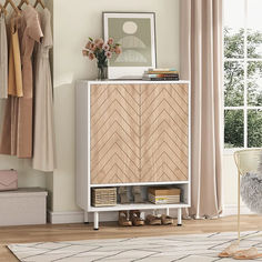 a white cabinet sitting in front of a window next to a rug and a chair