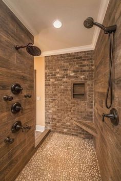 a walk in shower sitting next to a brick wall and tiled floor with two faucets