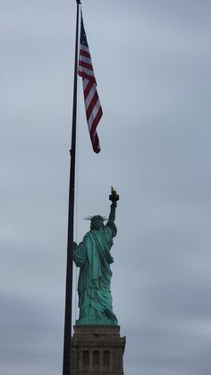 the statue of liberty is next to an american flag