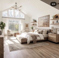 a large bedroom with white walls and wooden flooring, along with windows that look out onto the woods