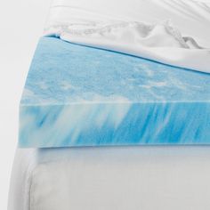 an unmade bed with blue and white sheets on top of it, next to a pillow