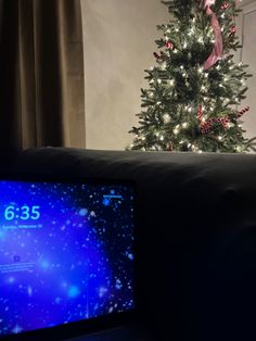 a christmas tree in the corner of a living room with a clock on it's side