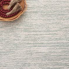 a bowl with beads and a tassel on it sitting on top of a rug