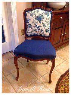 a blue chair sitting on top of a tile floor next to a wooden cabinet and sink