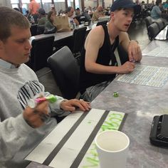 two young men sitting at a table playing monopoly