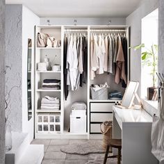 an open closet with clothes hanging on the shelves and drawers, along with a sink