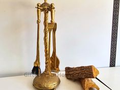 a golden candle holder with two candles and a piece of wood next to it on a white surface