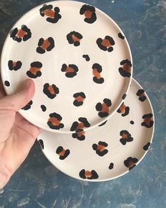 a hand is pointing at two plates with black and orange designs on them