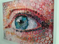 an art work made out of buttons and plastic bottles is displayed in a white frame