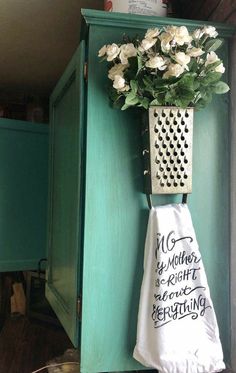 a teal cabinet with a white towel hanging from it's side and a bouquet of flowers on the door handle