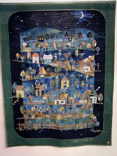 a quilted wall hanging with houses on it