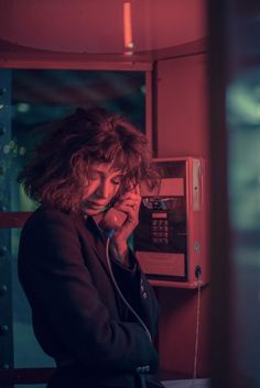 a woman is talking on the phone while standing in front of a wall mounted microwave