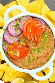 a white bowl filled with guacamole and sliced onions next to tortilla chips