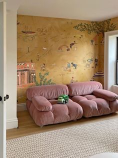 a pink couch sitting in front of a wall with pictures on it's walls