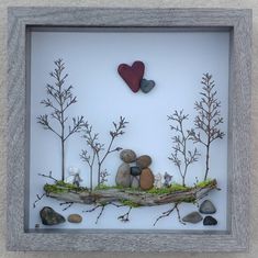 a shadow box with rocks and plants in it that has a heart on the top