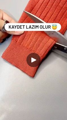 a person holding a pair of scissors in front of an orange knitted cloth with the words kaydet lazm ollur on it