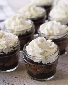 there are many desserts in small glass jars on the table, including one with whipped cream