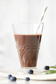 a glass filled with chocolate and blueberries on top of a table