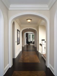 an empty hallway leading to another room with pictures on the wall and checkered floor