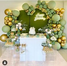 a birthday party with balloons, cake and desserts in front of a green backdrop