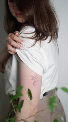 a woman with a small tattoo on her left arm and shoulder is looking down at the ground