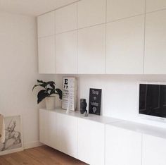 a kitchen with white cabinets and black appliances on the counter top, in front of a pink background