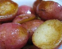 there is a white bowl filled with red and yellow potatoes that have been cooked in oil