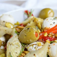 a white bowl filled with olives, artichokes and other food items