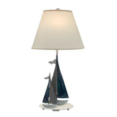 a lamp that is sitting on top of a white base with a sailboat design