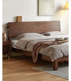 a bed sitting on top of a wooden floor next to a nightstand with a lamp