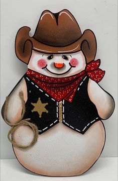 a snowman with a cowboy hat and star on it's chest holding a rope