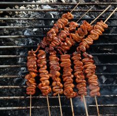 several skewers of food cooking on a grill