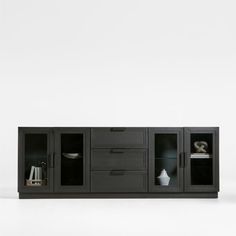 a black entertainment center with glass doors and drawers on each side, in front of a white wall