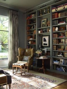 a living room filled with lots of furniture and bookshelves next to a window