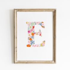 the letter e is made up of flowers and has been framed in a wooden frame