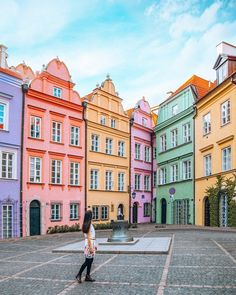 a woman standing in front of some colorful buildings