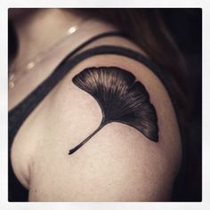 a black and white photo of a woman's arm with a leaf tattoo on it