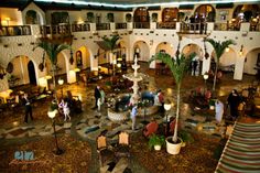 the inside of a hotel lobby with people walking around and sitting at tables in it