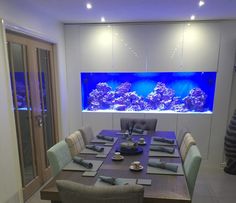 a dining room table is set with place settings for six and an aquarium in the background