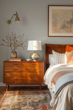 a bed sitting next to a wooden dresser with a lamp on it's side