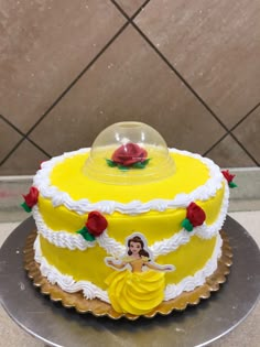 there is a yellow cake with white frosting and red roses on the top it